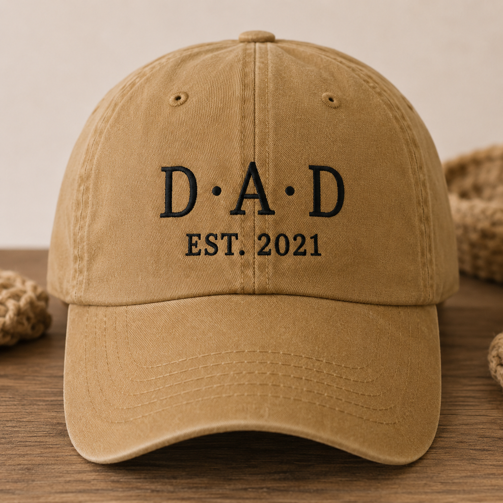 Brown cap with 'DAD EST. 2021' text on a wooden surface