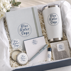Gift set with 'Blue Water Sage' branding including a tumbler, notebook, pen, and other items.