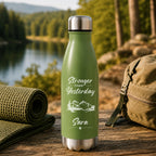 Green insulated bottle with 'Stronger Than Yesterday' text and mountain design, placed outdoors with a lake and forest in the background.