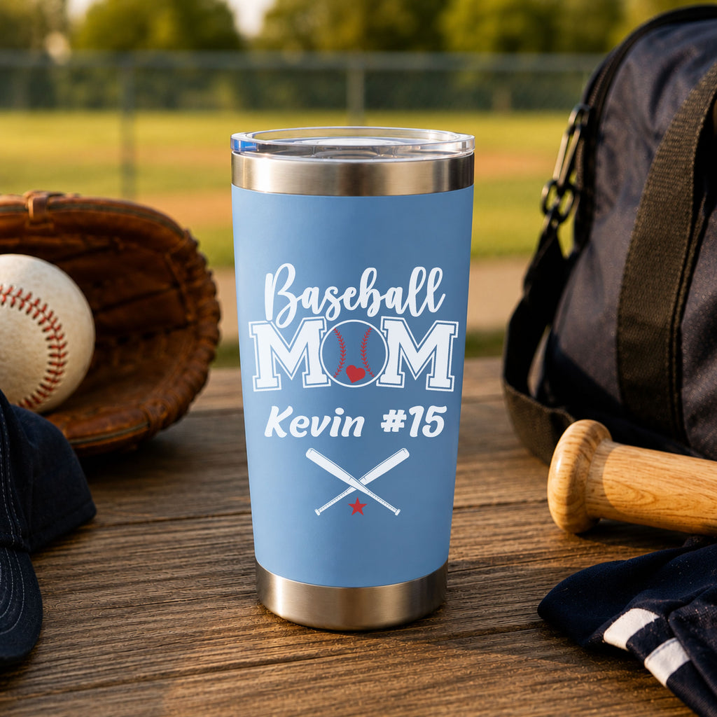 Blue tumbler with 'Baseball Mom Kevin #15' text on a wooden surface with baseball equipment.