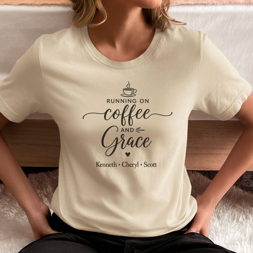 Person wearing a natural t-shirt with 'Running on Coffee and Grace' text with kids names sitting on floor by bed.