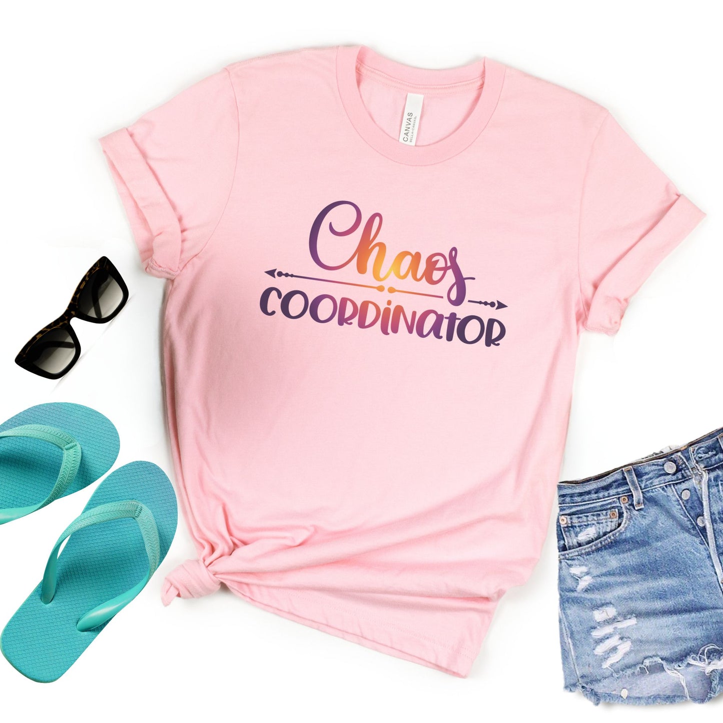 Flat lay pink t-shirt with multicolored texted in center with words Chaos Coordinator in center.