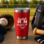 Red tumbler with 'Baseball Mom Stephen #7' text on a table with baseball equipment in the background.
